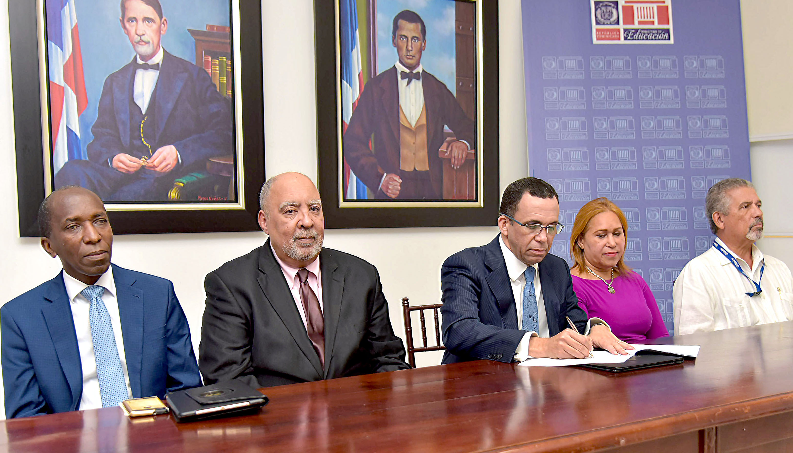  imagen Ministro Andr&eacute;s Navarro de pie traspasando al Director del ISFODOSU, documento que contempla gesti&oacute;n de 10 centros educativos para convertirlos en centros de excelencia, le acompa&ntilde;an viceministra Denia Burgos y directores INAFOCAM E IDEICE.&nbsp; 