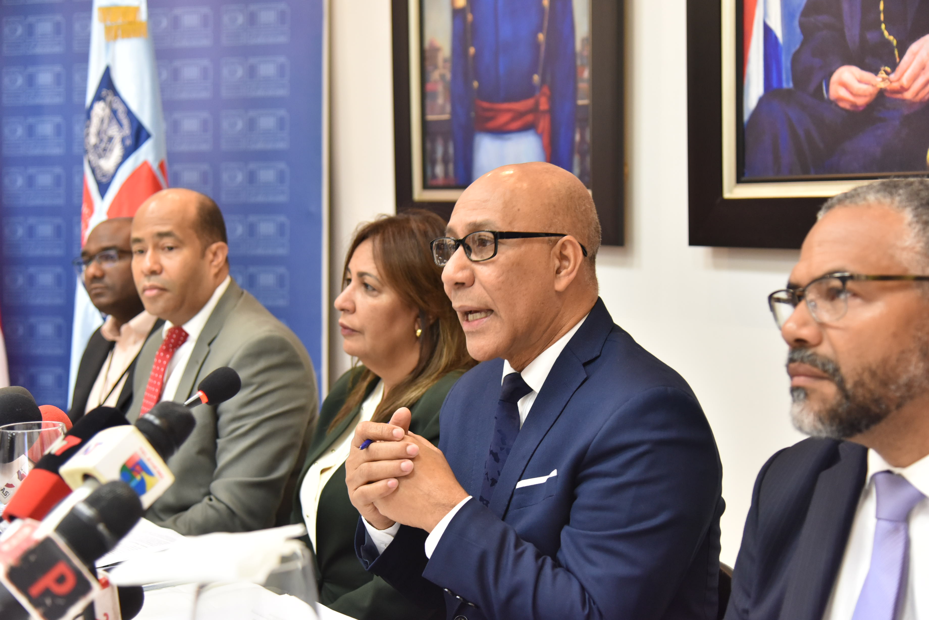  imagen Henry Santos junto a otras personalidades, sentados frente a la prensa durante rueda de prensa. 