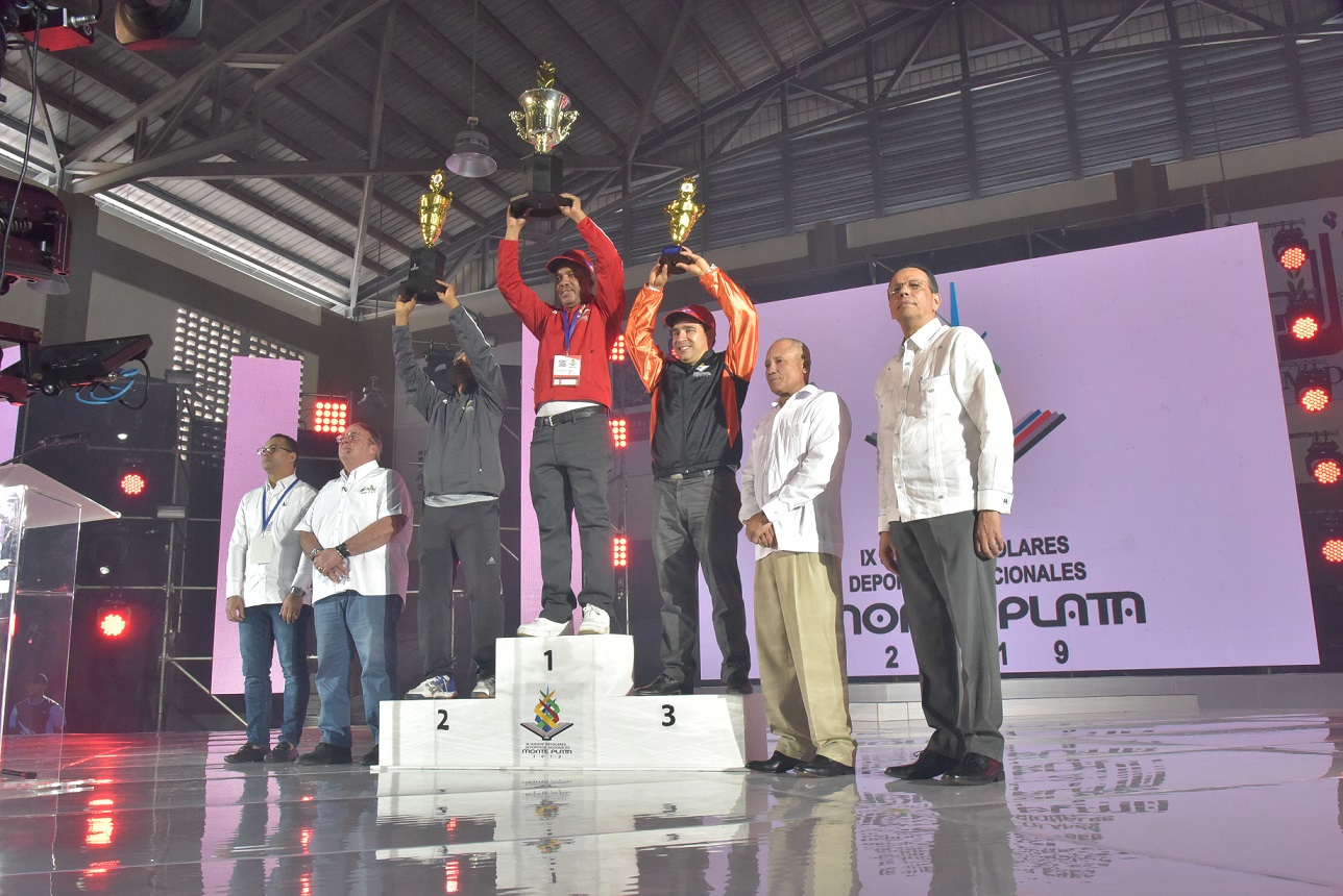  imagen Ministro Antonio Pe&ntilde;a Mirabal sostiene trofeo junto a equipo de atletas ganadores en Juegos Escolares Deportivos Nacionales Monte Plata 2019. A su lado, director de INEFI, Jorge Minaya. 