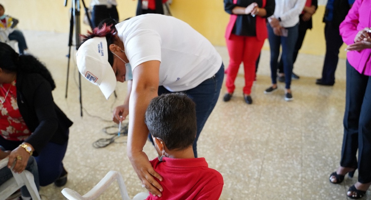  imagen Personal de vacunaci&oacute;n junto a estudiante, mostrando tarjeta de vacunaci&oacute;n a la c&aacute;mara. 