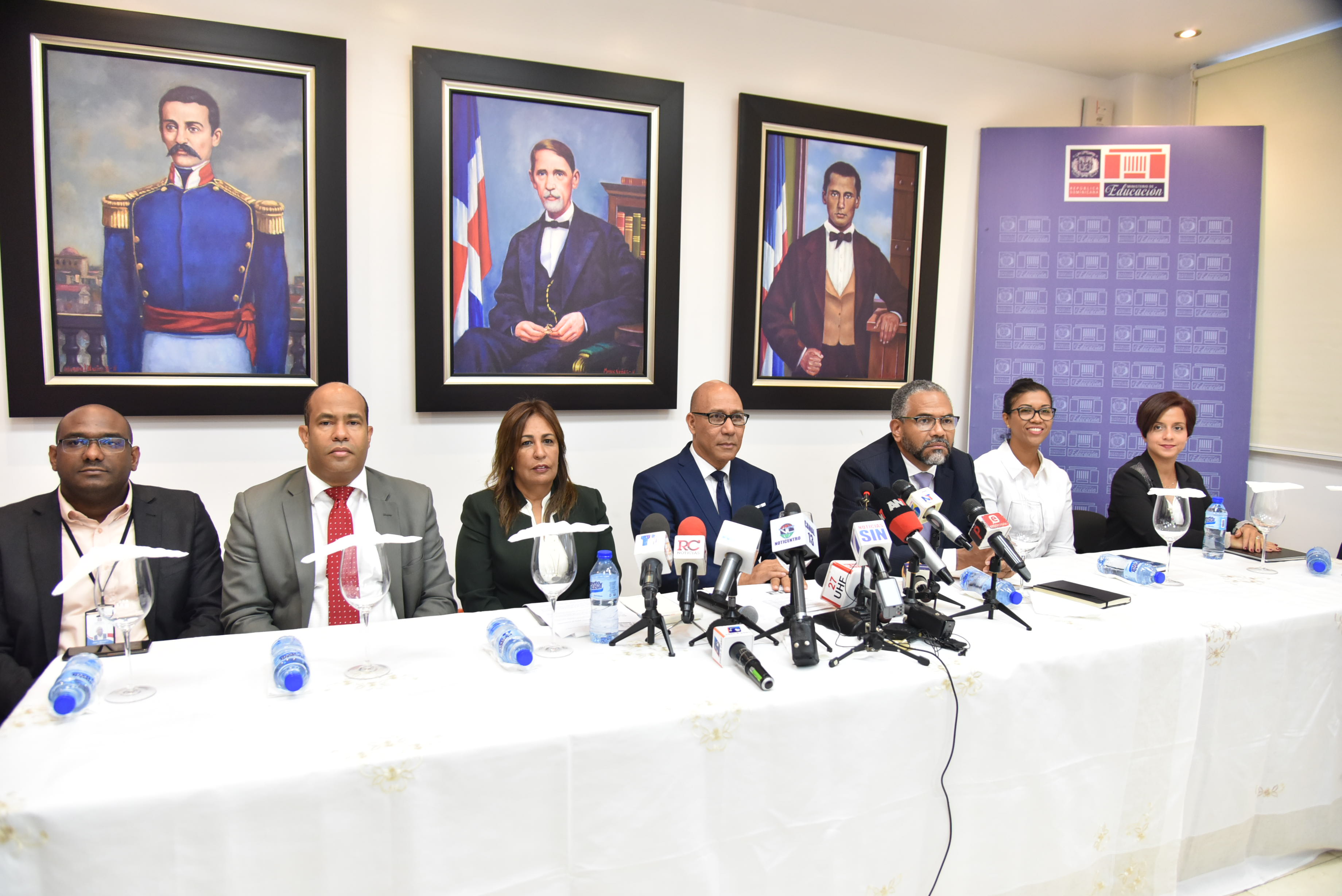  imagen Henry Santos junto a otras personalidades, sentados frente a la prensa durante rueda de prensa. 