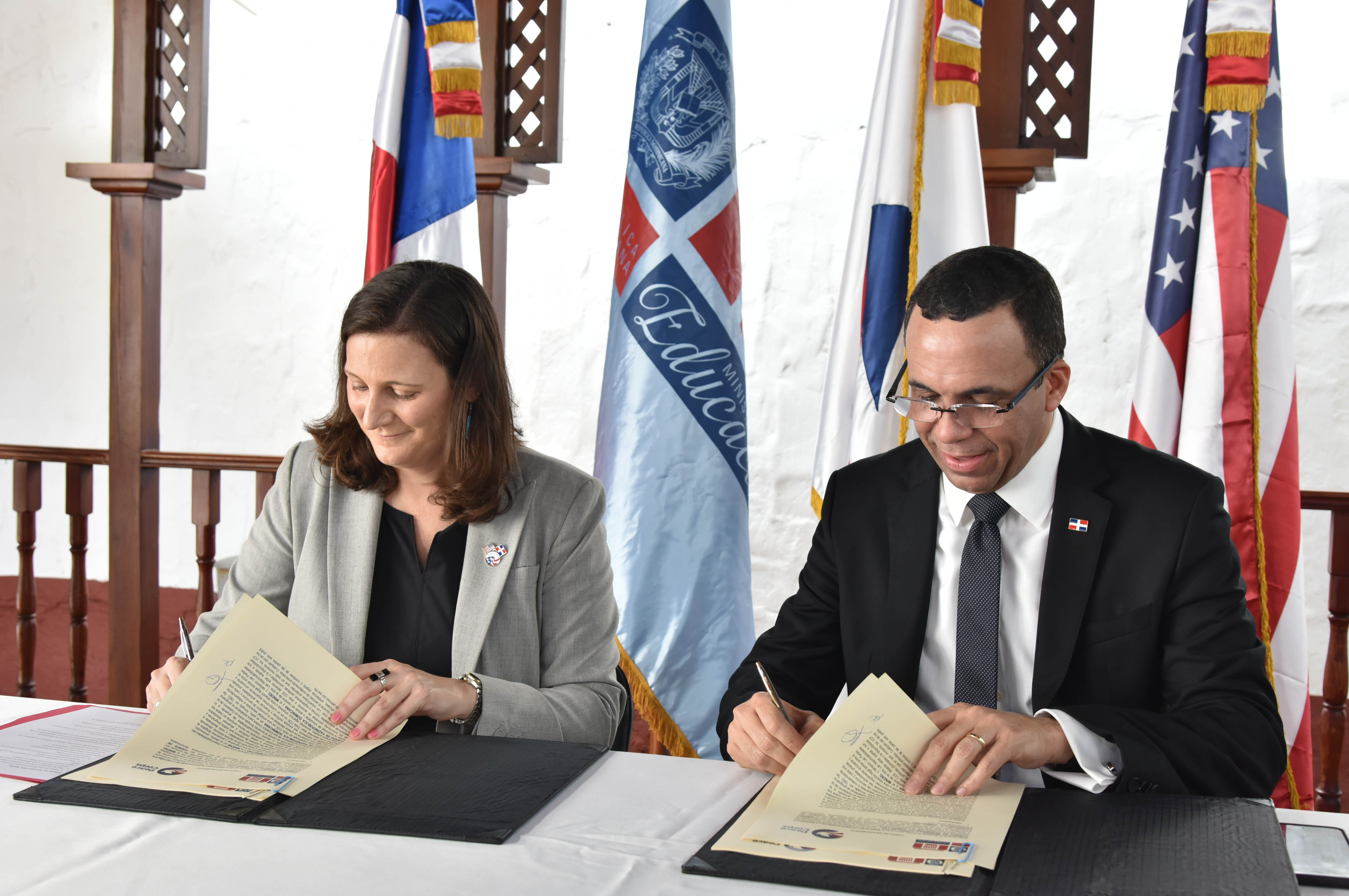  imagen Ministro Andr&eacute;s Navarro y la representante del Cuerpo de Paz de Estados Unidos, Kristin Kaper sentados firmando acuerdo de entendimiento para llevar voluntarios a las escuelas.&nbsp; 