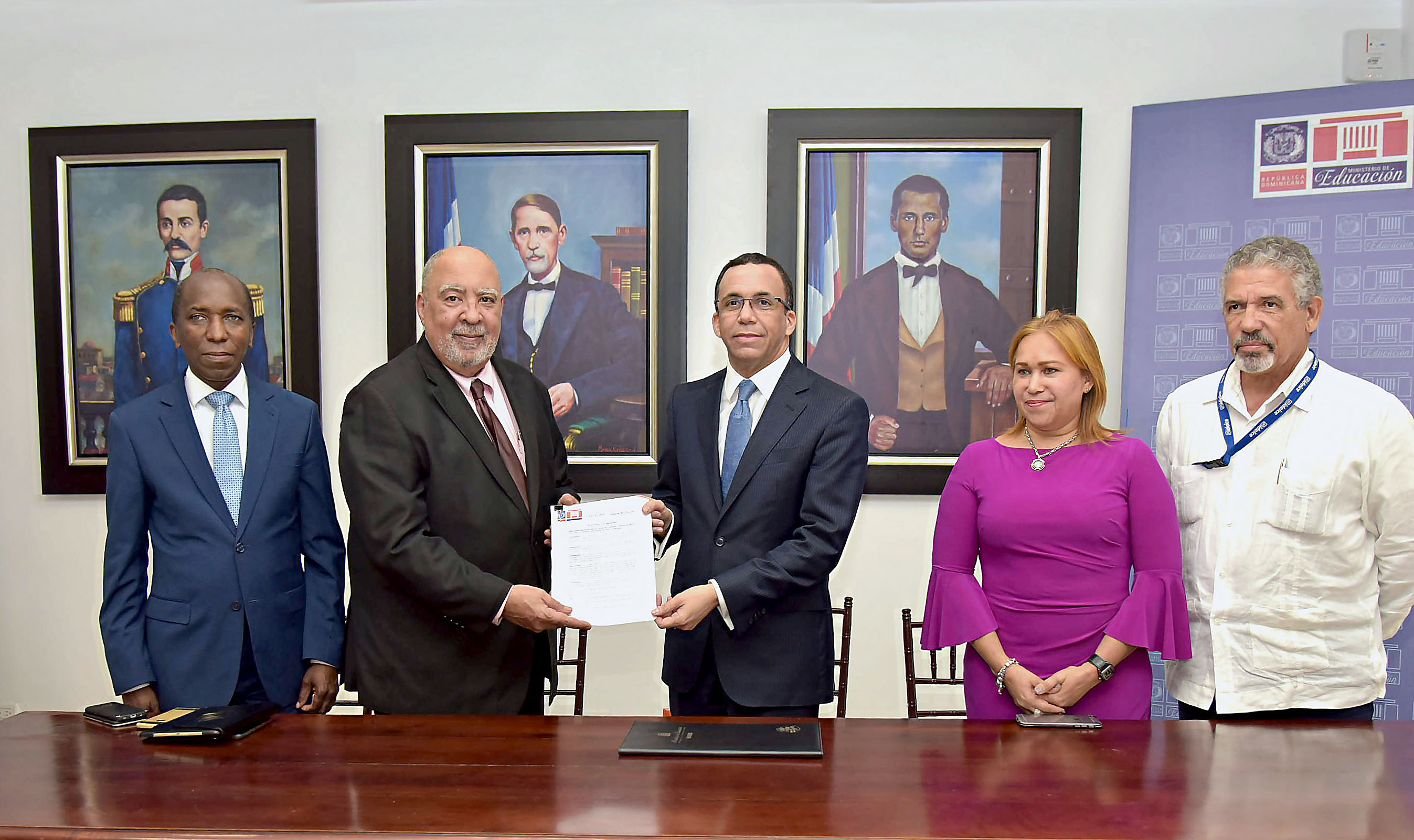  imagen Ministro Andr&eacute;s Navarro de pie traspasando al Director del ISFODOSU, documento que contempla gesti&oacute;n de 10 centros educativos para convertirlos en centros de excelencia, le acompa&ntilde;an viceministra Denia Burgos y directores INAFOCAM E IDEICE.&nbsp; 