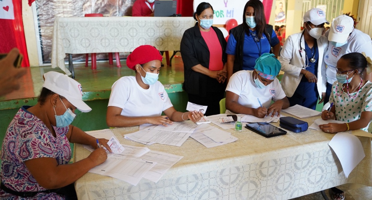  imagen Personal de vacunaci&oacute;n junto a estudiante, mostrando tarjeta de vacunaci&oacute;n a la c&aacute;mara. 