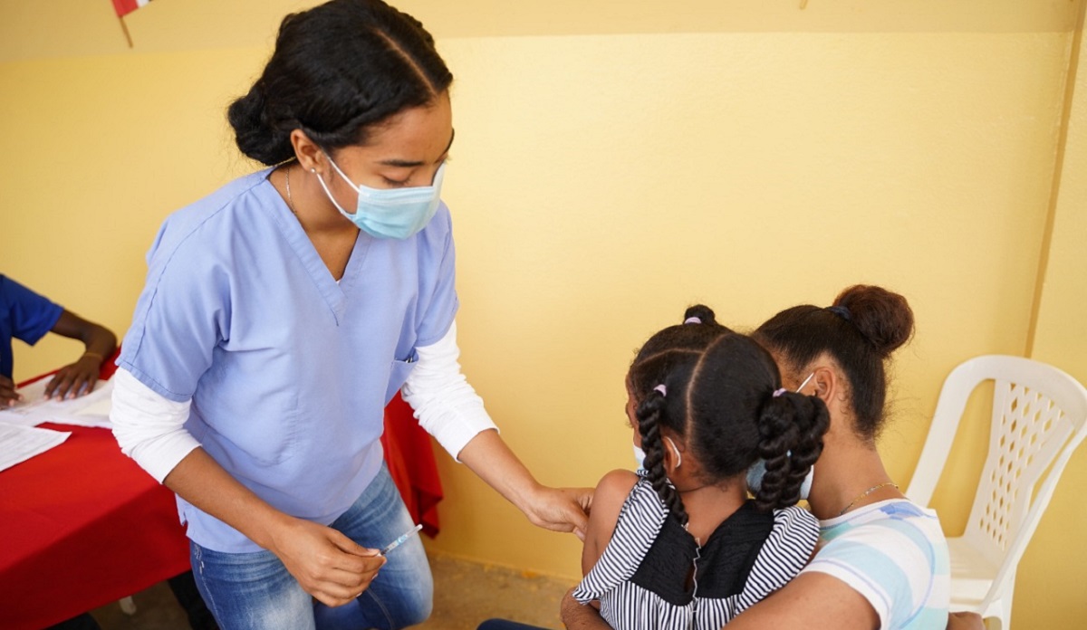  imagen Personal de vacunaci&oacute;n junto a estudiante, mostrando tarjeta de vacunaci&oacute;n a la c&aacute;mara. 