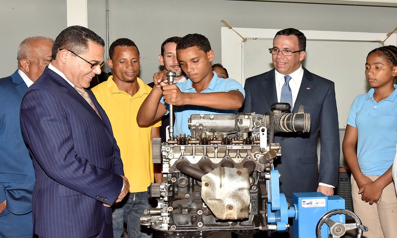 imagen Ministro de educaci&oacute;n Andres Navarro junto a director Rafael Ovalles y&nbsp; grupo de estudiantes de Infotep. Uno de los estudiantes realiza una demostraci&oacute;n flojando tuerca de un motor. 