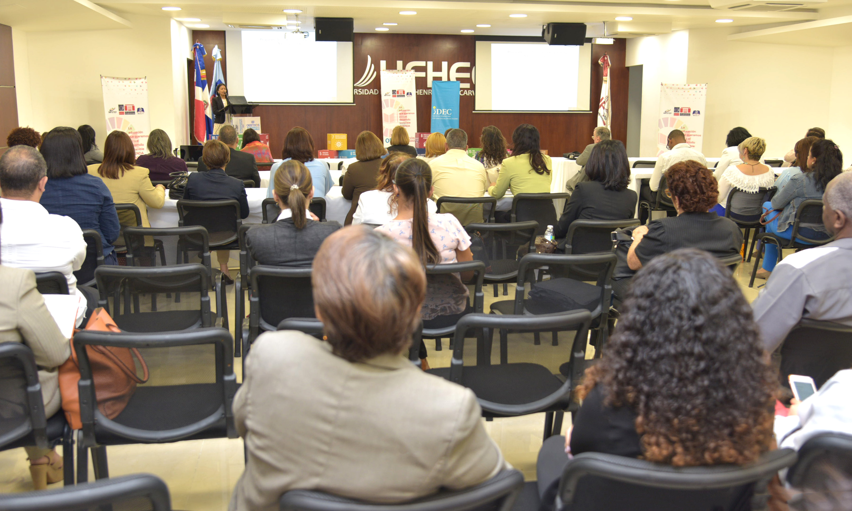  imagen &nbsp;Mujer de pie en podium dirigiendo discurso sobres los ODS 