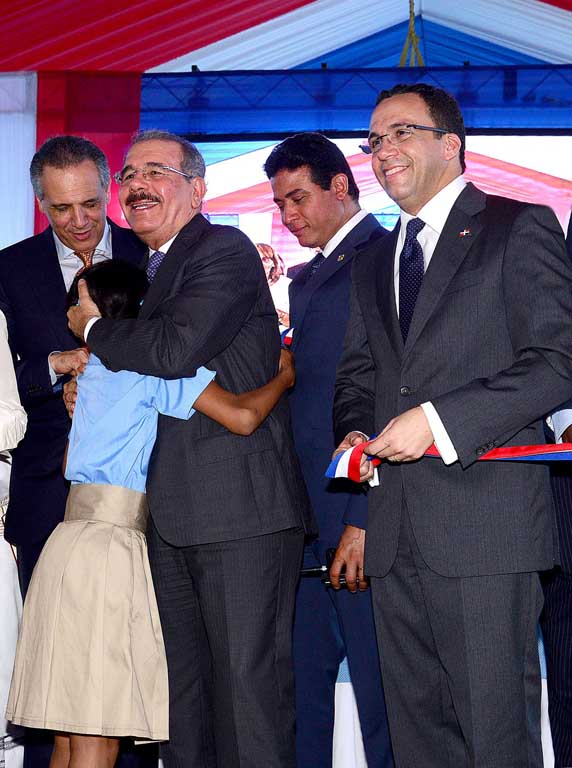  imagen Presidente Danilo Medina sonriente abraza una estudiante. A su lado el Ministro Andr&eacute;s Navarro, entre otras personalidades. 