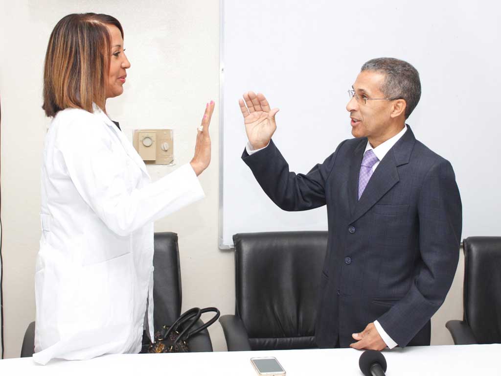  imagen Momento de juramentaci&oacute;n de doctora Adames Chapman por doctor Enriquillo Matos. Ambos con mano derecha alzada a nivel de los hombros. 