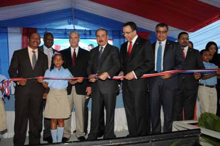  imagen Presidente Danilo Medina mientras corta cinta en acto de inauguraci&oacute;n, a su lado izquierdo Ministro Andr&eacute;s Navarro sostiene un extremo de la cinta; con ellos otras personalidades invitadas. 